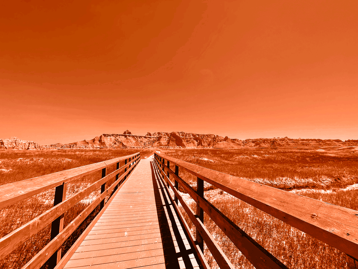 Image of boardwalk with mountains in background, with an orange hue